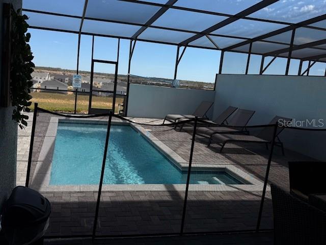 pool featuring glass enclosure and a patio