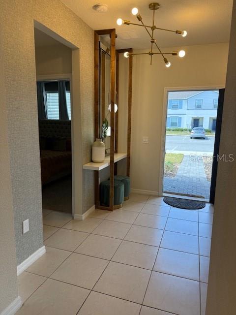 doorway to outside featuring a healthy amount of sunlight, light tile patterned floors, and baseboards