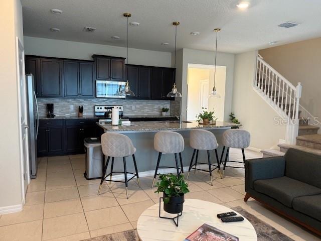 kitchen featuring stainless steel appliances, visible vents, a kitchen breakfast bar, and light tile patterned floors