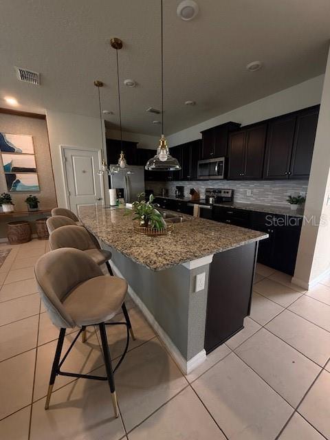 kitchen featuring light tile patterned floors, visible vents, appliances with stainless steel finishes, and light stone counters