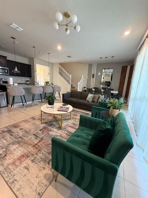 living area featuring recessed lighting, visible vents, stairway, an inviting chandelier, and light tile patterned flooring