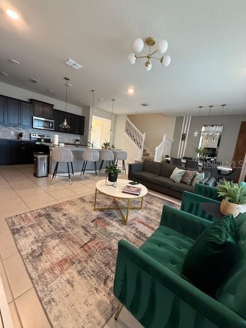 living room featuring stairs, light tile patterned flooring, and visible vents