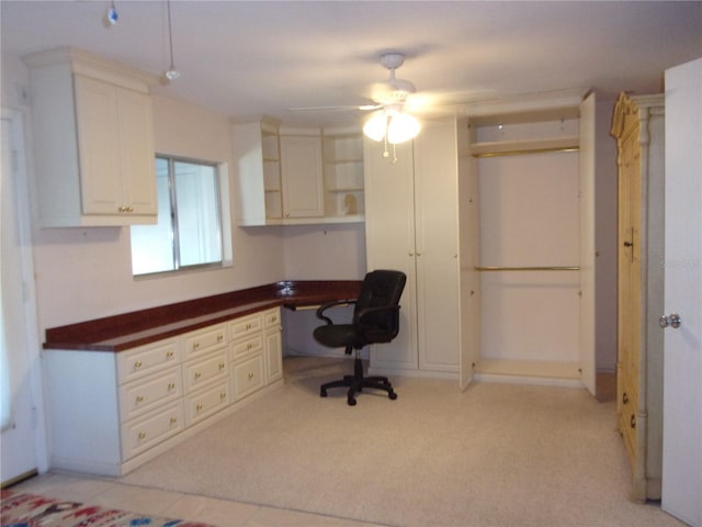 home office featuring ceiling fan, built in desk, and light colored carpet