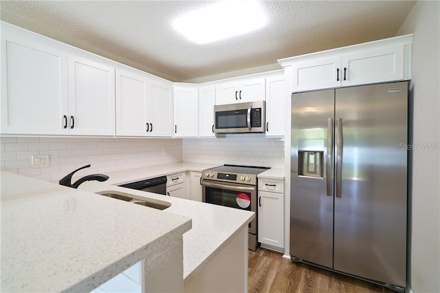 kitchen with backsplash, dark wood finished floors, stainless steel appliances, white cabinets, and light stone countertops