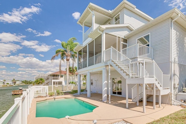 back of property featuring a fenced in pool, a sunroom, a patio area, fence, and stairs