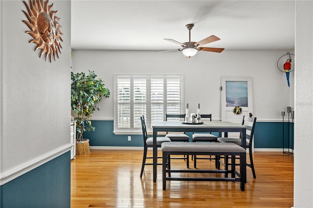 dining area with baseboards, a ceiling fan, and wood finished floors