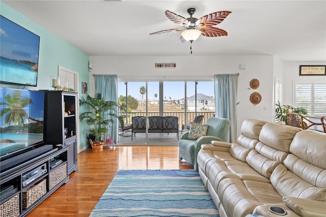 living area with wood finished floors, a wealth of natural light, and a ceiling fan