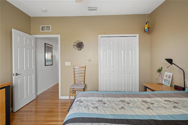 bedroom featuring baseboards, a closet, visible vents, and wood finished floors