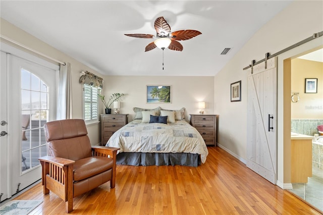 bedroom with a barn door, baseboards, visible vents, connected bathroom, and light wood-type flooring