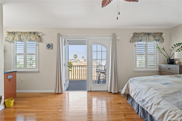 bedroom featuring baseboards, multiple windows, light wood-type flooring, and access to exterior