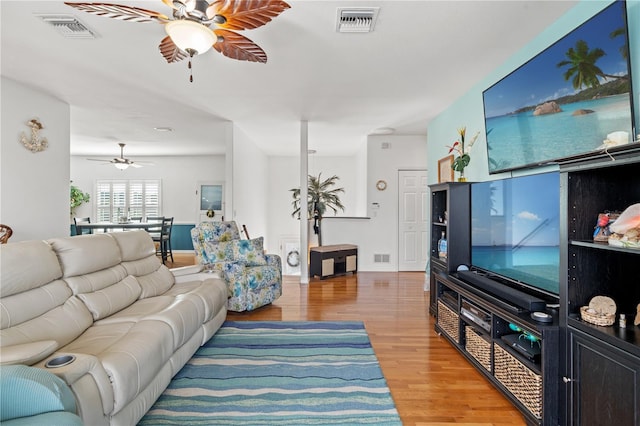 living area with light wood-type flooring, visible vents, and a ceiling fan