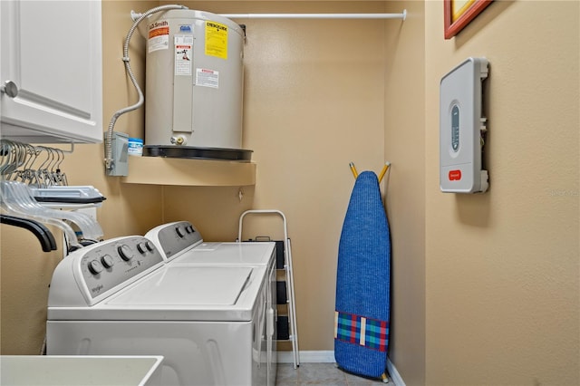 washroom featuring washing machine and dryer, cabinet space, baseboards, and water heater