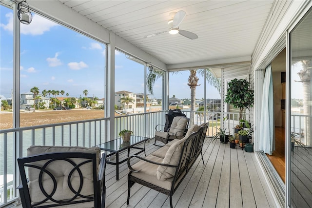 sunroom / solarium with a residential view and a ceiling fan