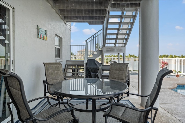 view of patio with outdoor dining area, fence, and stairs