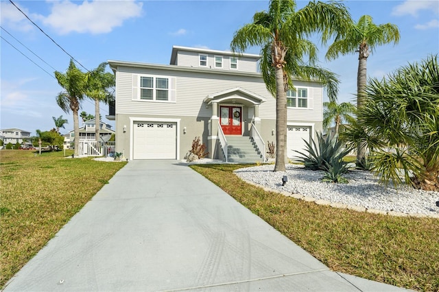 coastal home featuring a garage, a front yard, driveway, and stucco siding