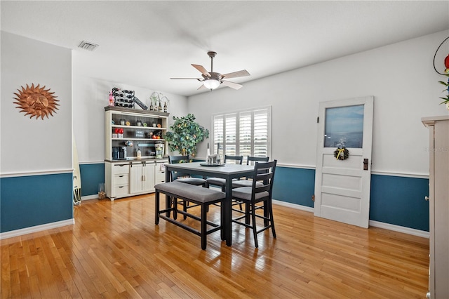 dining area featuring baseboards, visible vents, a ceiling fan, and light wood-style flooring