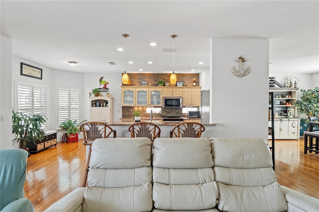 living area with visible vents, recessed lighting, and light wood-style flooring