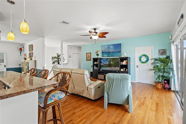 living area with visible vents, light wood-type flooring, and ceiling fan
