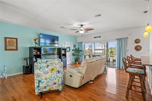 living room featuring a ceiling fan, visible vents, hardwood / wood-style flooring, and baseboards