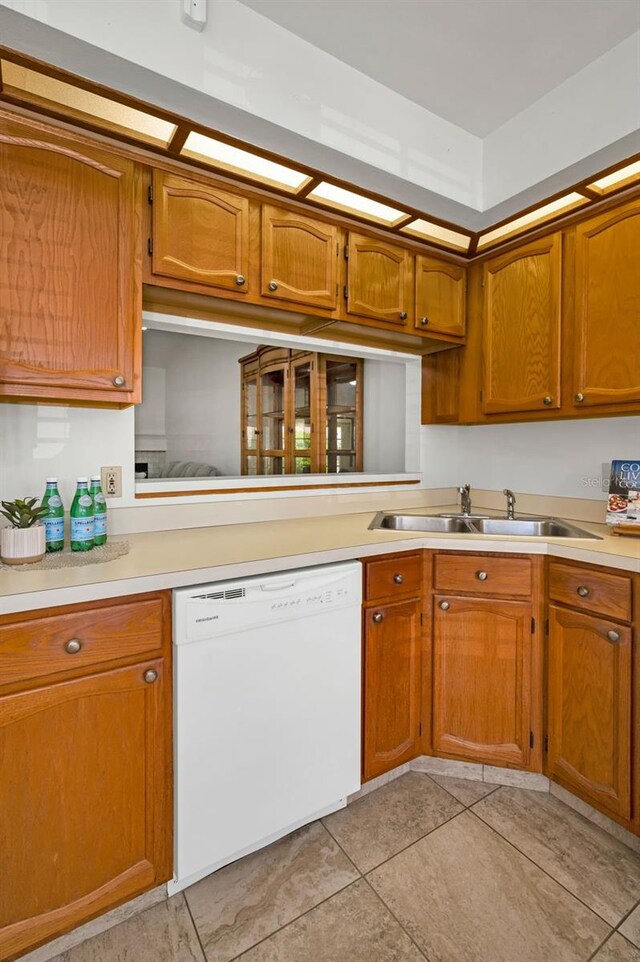 2446 Bentley Dr, Palm Harbor, FL 34684 - kitchen with light countertops, dishwasher, a sink, brown cabinetry, and light tile patterned floors
