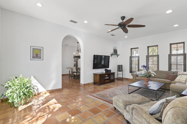 living area featuring recessed lighting, visible vents, arched walkways, baseboards, and ceiling fan with notable chandelier