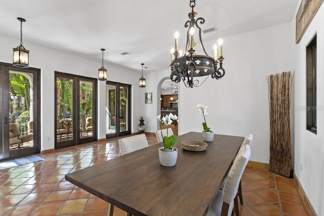 tiled dining space with arched walkways, french doors, visible vents, and baseboards