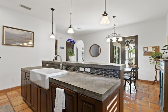 kitchen with arched walkways, visible vents, a sink, and dark countertops