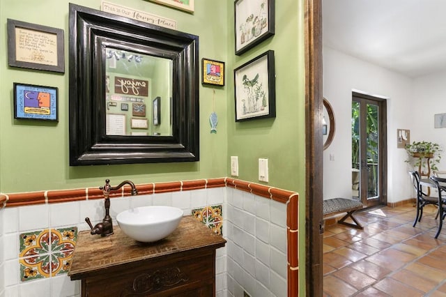 bathroom with a wainscoted wall, tile walls, vanity, and tile patterned floors