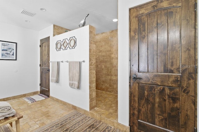 bathroom with baseboards, visible vents, and walk in shower