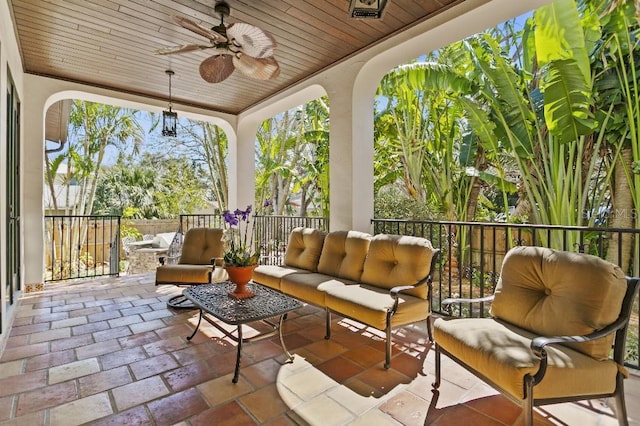 sunroom featuring wood ceiling and a ceiling fan