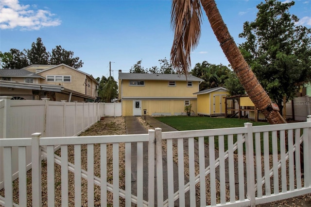 view of front facade with an outbuilding, a fenced backyard, a front yard, and a storage unit