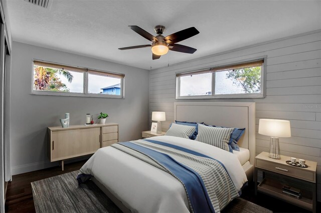 7 Georgia Ave, Crystal Beach, FL 34681 - bedroom with wooden walls, a ceiling fan, visible vents, baseboards, and dark wood finished floors