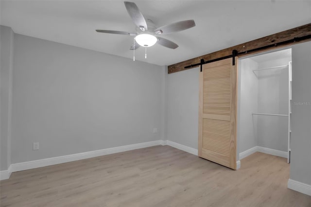 7 Georgia Ave, Crystal Beach, FL 34681 - unfurnished bedroom with a ceiling fan, a barn door, a closet, light wood finished floors, and baseboards