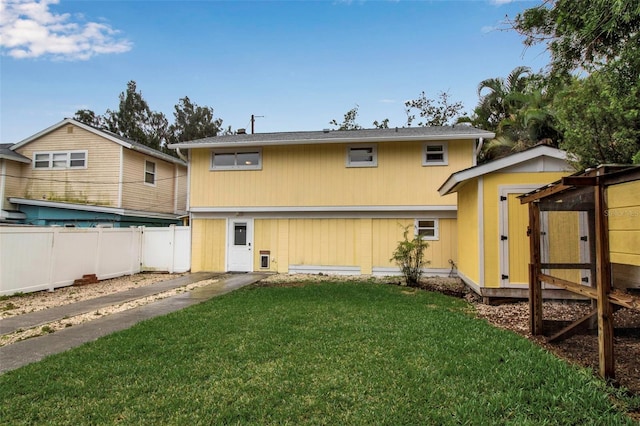 rear view of house with fence, a lawn, and an outdoor structure