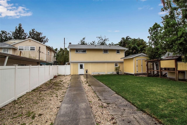 back of house with an outbuilding, a lawn, and fence