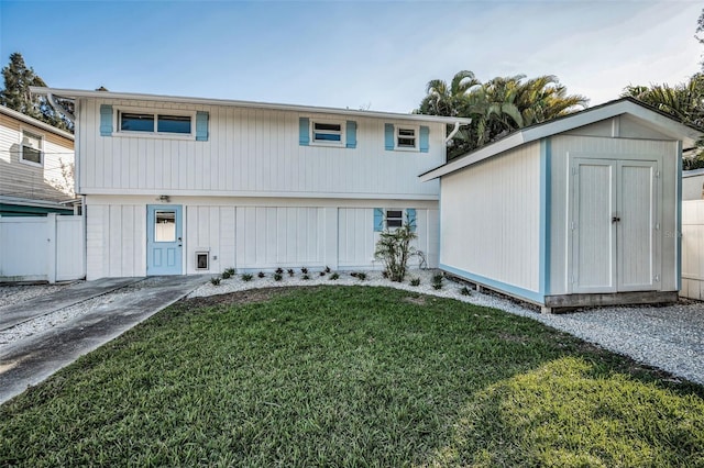 view of front of property featuring a front lawn, a storage unit, fence, and an outdoor structure