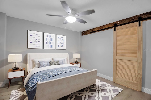 7 Georgia Ave, Crystal Beach, FL 34681 - bedroom featuring light wood finished floors, ceiling fan, baseboards, and a barn door