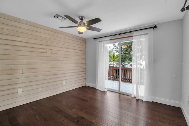 7 Georgia Ave, Crystal Beach, FL 34681 - spare room with visible vents, baseboards, dark wood finished floors, wood walls, and a ceiling fan