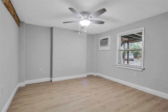 7 Georgia Ave, Crystal Beach, FL 34681 - spare room with a ceiling fan, baseboards, light wood finished floors, a wall mounted AC, and a textured ceiling