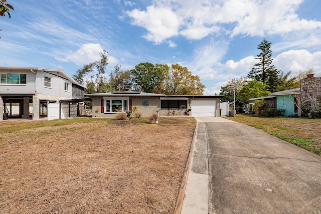 view of front of property with driveway, a front lawn, an attached garage, and roof mounted solar panels