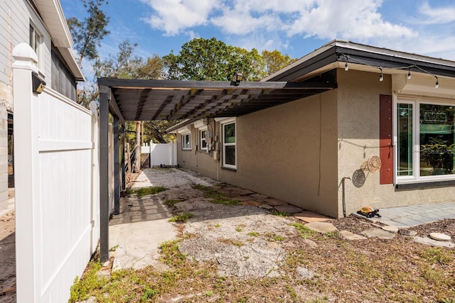 view of side of home featuring a patio area, fence, and stucco siding