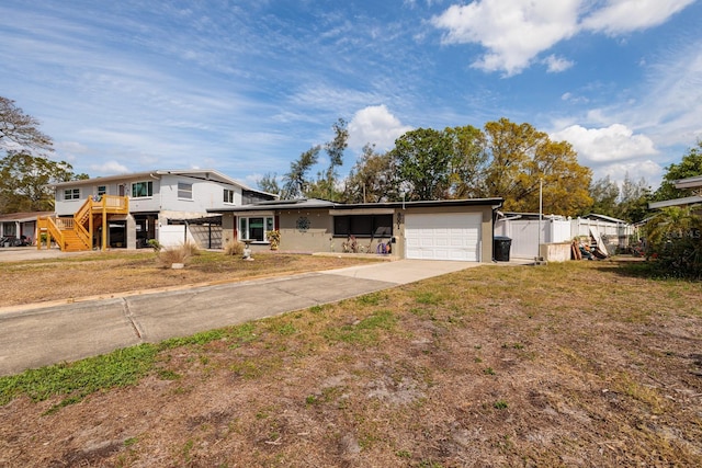 view of front of property featuring driveway, a garage, and fence