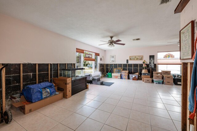 living room featuring light tile patterned flooring, visible vents, and a ceiling fan