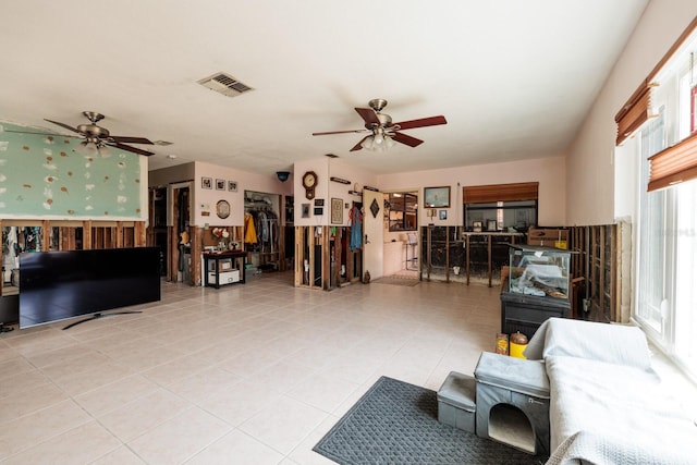 living area with a ceiling fan, visible vents, and tile patterned floors