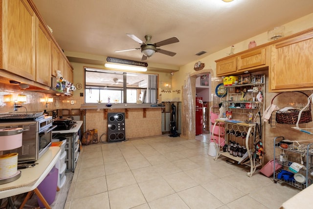 kitchen featuring a toaster, visible vents, a ceiling fan, a wainscoted wall, and light tile patterned flooring