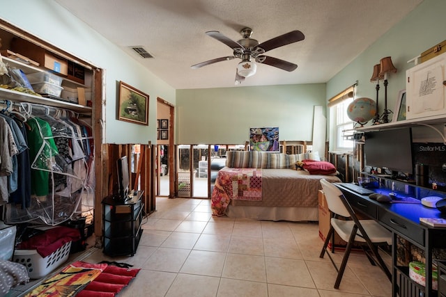 bedroom with a ceiling fan, visible vents, a textured ceiling, and light tile patterned floors