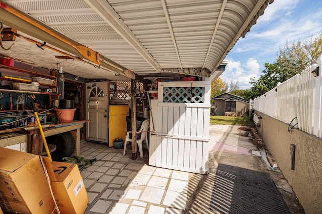 view of patio with an outbuilding, fence, and a shed