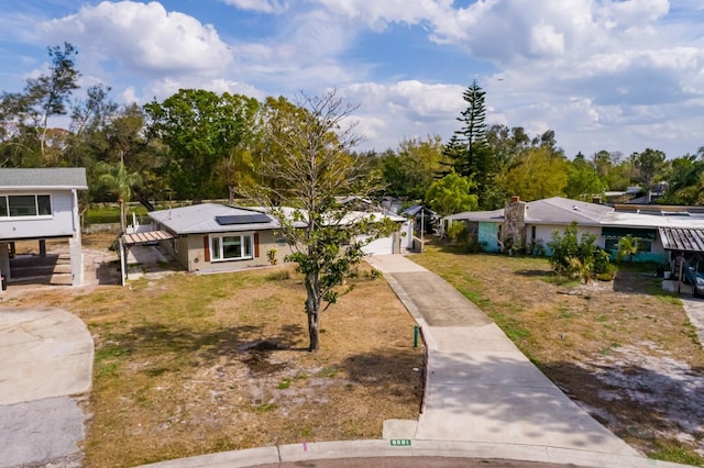 view of front of property featuring a garage, driveway, solar panels, and a front yard