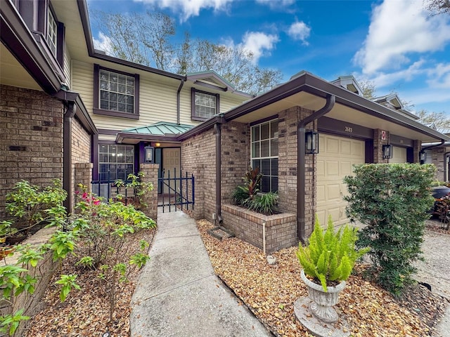 entrance to property featuring a garage and brick siding