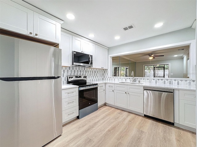 kitchen featuring stainless steel appliances, a sink, visible vents, light wood-type flooring, and tasteful backsplash